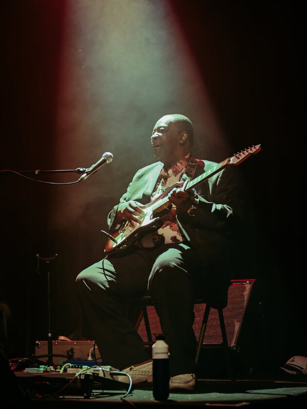 portrait de Dizzy Mandjeku avec sa guitare